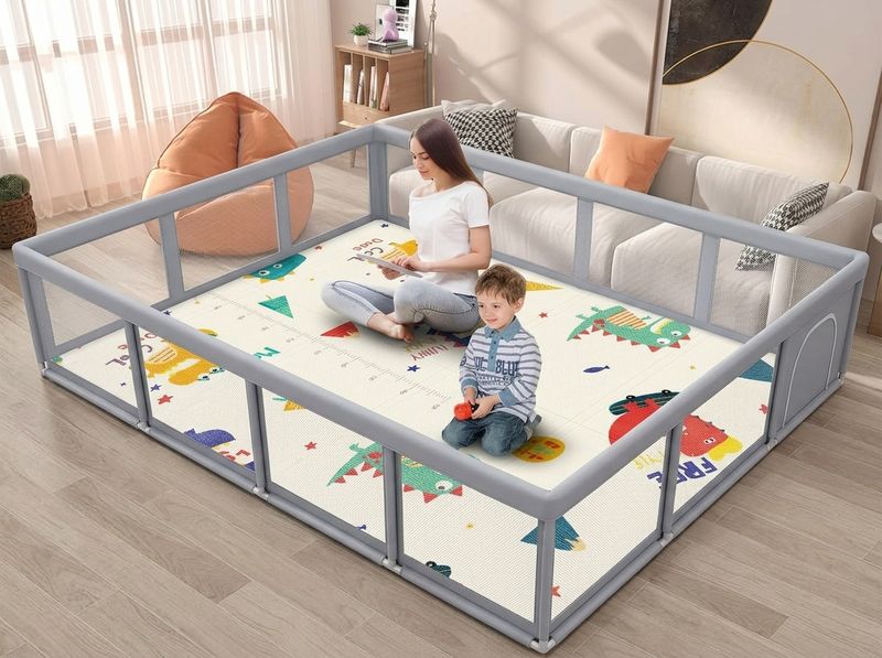 Overhead shot of the 74×50 Fshibila reversible foam mat dropped flush inside the matching 74×50 playpen, parent's hand smoothing the corner
